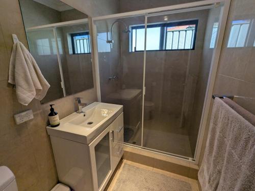 パースにあるLake Estate Stayのシャワーと洗面台を備えた白いバスルーム