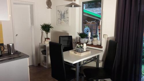 a dining room with a white table and black chairs at Ferienwohnung Sonneneck mit Boot und Kanu in Seedorf