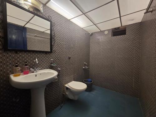 a bathroom with a sink and a toilet and a mirror at Baga Waves by Dia Hotels And Homes in Calangute