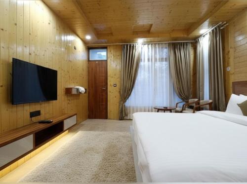 a hotel room with a bed and a tv at Chatnya Homes Kasauli by Splendid Hotels - Family Groups Events in Kasauli