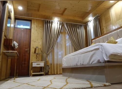 a bedroom with a bed and a large window at Chatnya Homes Kasauli by Splendid Hotels - Family Groups Events in Kasauli