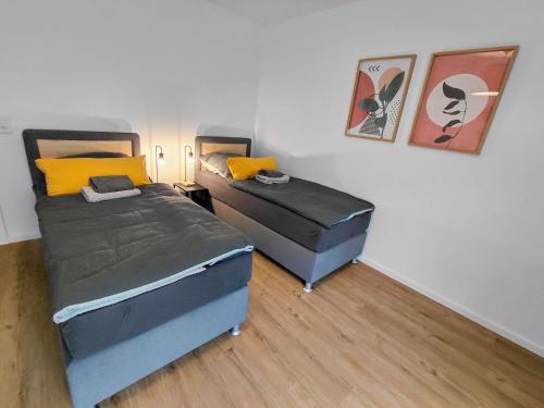 HalverにあるWestfalio Apartments - BrightStay Halver - feel at homeの壁に絵画が飾られた小さな部屋のベッド2台
