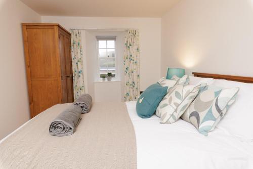 a bedroom with a white bed with pillows and a window at Auld Haa Apartments, Shetland Islands in Scalloway
