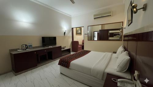 una habitación de hotel con una cama y un televisor en Makran Palace Hotel, en Ma‘ābīlah