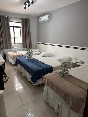 a room with three beds in a room at Alzira Plaza Hotel in São Lourenço