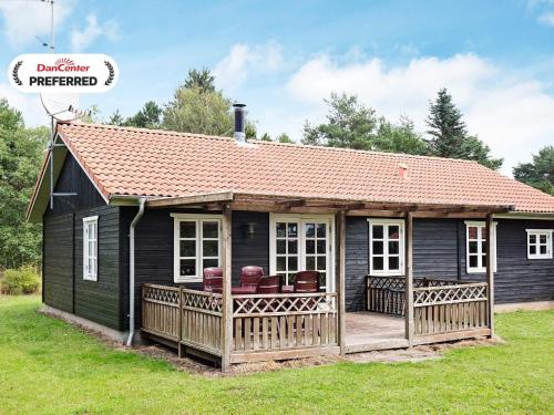 a small black house with a wooden deck at 8 person holiday home in Rødby-By Traum in Kramnitse
