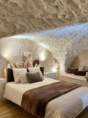 a bedroom with two beds in a stone wall at Le Cocon Secret in Saint-Cyr