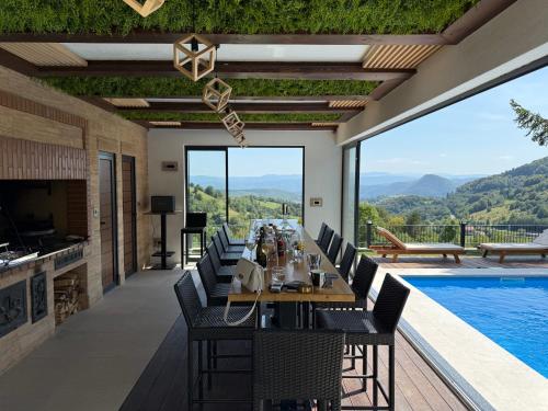 a dining room with a table and chairs and a pool at Mountain House LISINSKA ROSA in Brdo