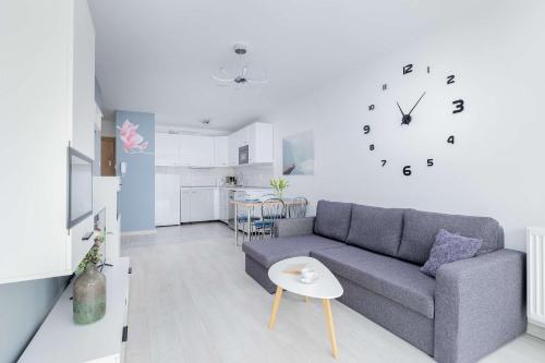 ein Wohnzimmer mit einer Couch und einer Uhr an der Wand in der Unterkunft Perłowa Przystań Unique Apartment with Air Conditioning and Parking Space in Kołobrzeg by Noclegi Renters in Radzikowo
