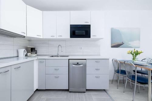 eine weiße Küche mit einem Waschbecken und einem Tisch in der Unterkunft Perłowa Przystań Unique Apartment with Air Conditioning and Parking Space in Kołobrzeg by Noclegi Renters in Radzikowo