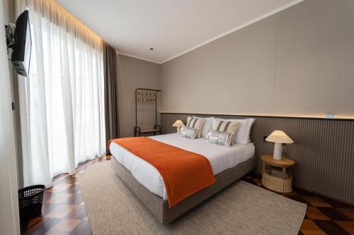 a bedroom with a large bed with an orange blanket at GuestReady - Gaveto de Lisboa GuestHouse in Ponta Delgada