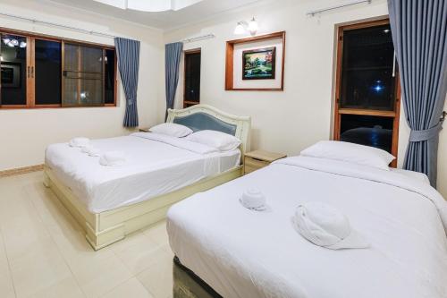 zwei Betten in einem Zimmer mit zwei Fenstern in der Unterkunft D Pool Villa Pattaya in Nong Prue