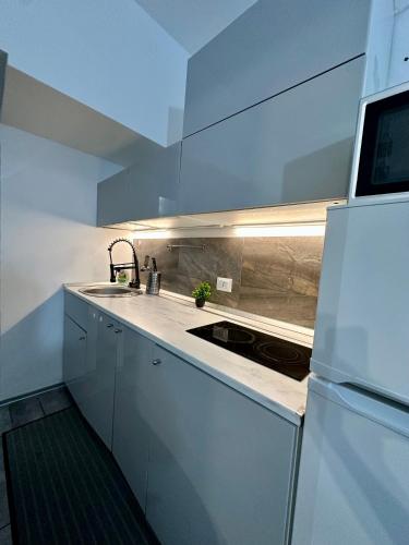 een witte keuken met een wastafel en een koelkast bij Affori- Apartment Milan in Milaan