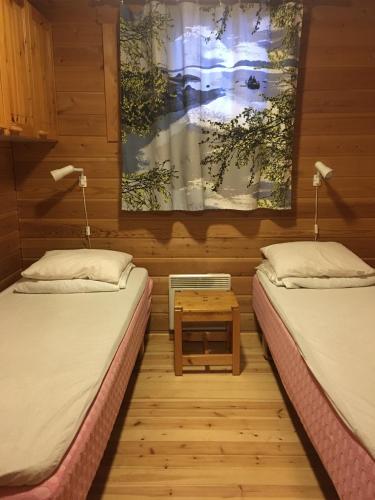 two twin beds in a room with a table at Immelmökit in Levi