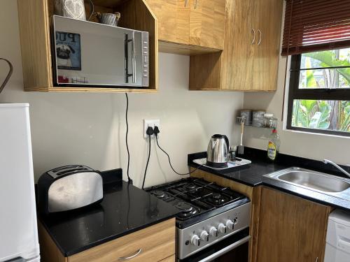 eine kleine Küche mit Herd und Spüle in der Unterkunft Khaled Estate Cottages in Hillcrest