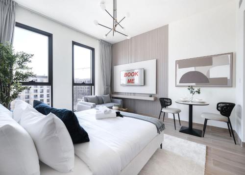 a bedroom with a white bed and a table and chairs at StayShort - Town Square sleeps 2 in Great Location in ‘Ūd al Bayḑāʼ