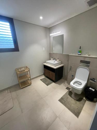 a bathroom with a white toilet and a sink at Golden Dawn Villa in As Sīfah