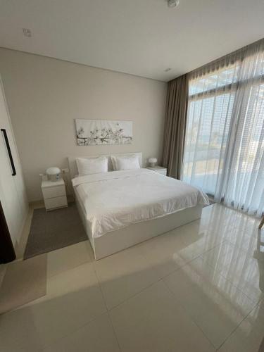 a white bedroom with a bed and a large window at Golden Dawn Villa in As Sīfah