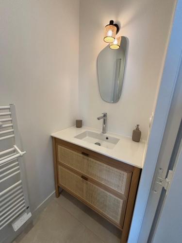 ein Badezimmer mit Waschbecken und Spiegel in der Unterkunft Suite hôtelière face à la mer in Santec