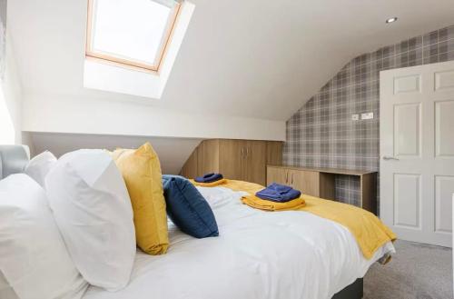 a bedroom with a white bed with yellow and blue pillows at Oxheys Stays - Sleeps 7 - Home from Home in Preston