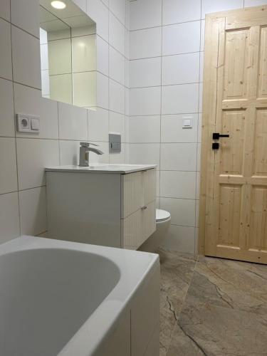 een badkamer met een wastafel, een toilet en een spiegel bij Harrachovský Chalet u sjezdovky 