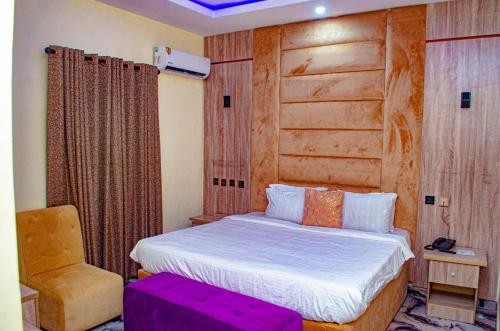 a bedroom with a bed with a wooden headboard and a chair at Bremmy Multilinks Hotels and Suites in Asaba
