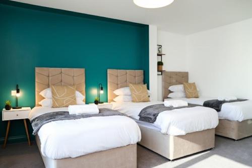 two beds in a room with a green wall at Syster Properties Modern Leicester Stay with Free Parking LE2 Area in Leicester
