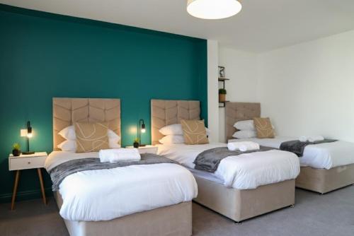 a bedroom with two beds and a green wall at Syster Properties Modern Leicester Stay with Free Parking LE2 Area in Leicester