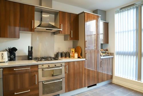 a kitchen with wooden cabinets and a stove top oven at Syster Properties Modern Leicester Stay with Free Parking LE2 Area in Leicester