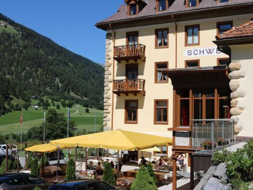 ein Hotel mit Tischen und Sonnenschirmen vor einem Gebäude in der Unterkunft Hotel Schweizerhof Sta Maria in Sta Maria Val Müstair