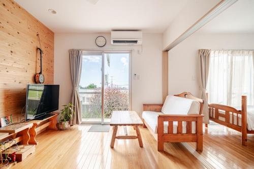 a living room with a couch and a tv at お子様連れ&動物好き大歓迎！産みたての卵を収穫体験できる宿 in Nanjo