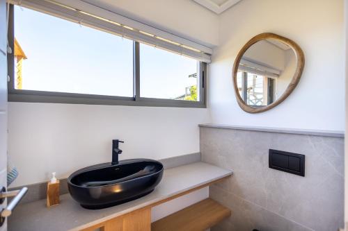 ein Badezimmer mit einem schwarzen Waschbecken und einem Spiegel in der Unterkunft Dune Seaside Cottage in Plettenberg Bay