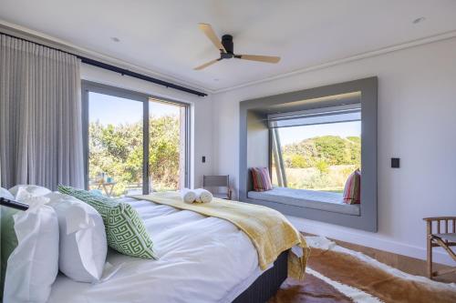 ein Schlafzimmer mit einem großen Bett mit einem großen Fenster in der Unterkunft Dune Seaside Cottage in Plettenberg Bay
