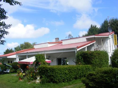 Biały dom z czerwonym dachem w obiekcie Agroturystyka Chłopy w Sarbinowie