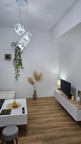 a white living room with a table and a tv at Airport Nest Skopje in Petrovec