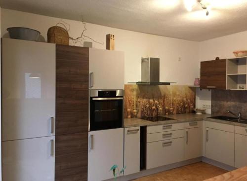 a kitchen with white cabinets and black appliances at Ferienhaus Im Grünen in Zella-Mehlis