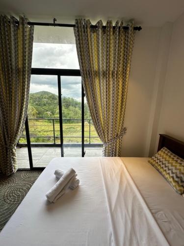een slaapkamer met een bed en een groot raam bij The Green Garniya Poolside and Mountain View Hotel in Belihul Oya