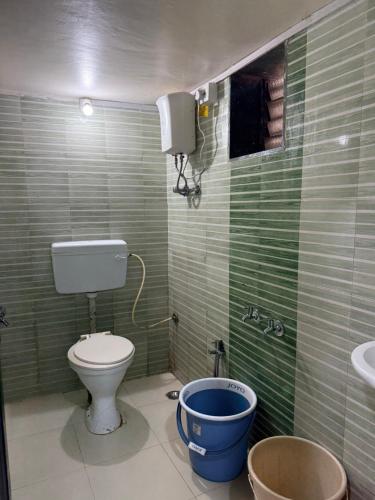 a bathroom with a toilet and a bucket in it at Patil residency in Matheran