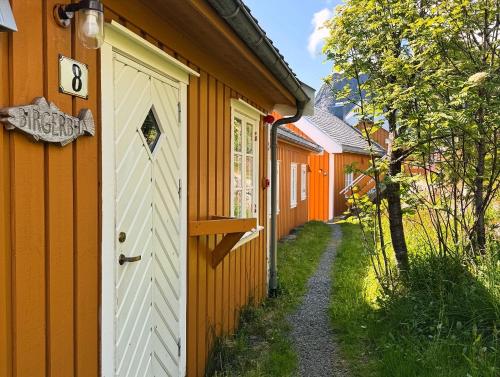 a row of orange buildings with a door at Sakrisøy Rorbuer in Reine