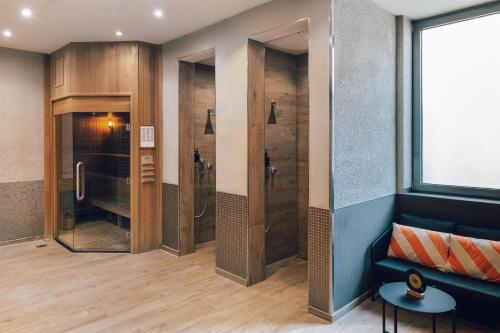 a bathroom with a walk in shower and a couch at Pentahotel Leipzig in Leipzig