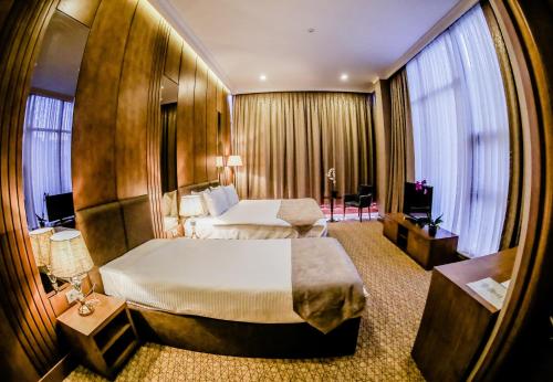 a hotel room with two beds and a large window at Adisson Hotel Baku in Azadliq avenue in Baku