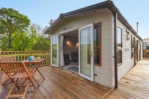 a small shed with a table and a chair on a deck at Greendale Splash Escape - No Commercial Sign written Vehicles,Fishing Nearby & Communal Swimming Pool Open April to September in Tedburn Saint Mary