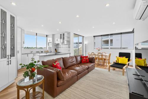 クロヌラにあるThe Oceanfront Sanctuary Spa & Parkingのリビングルーム(ブラウンソファ付)、キッチンが備わります。