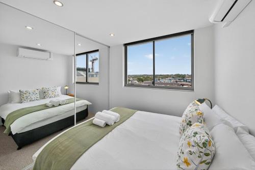 a bedroom with two beds and two windows at The Oceanfront Sanctuary Spa & Parking in Cronulla