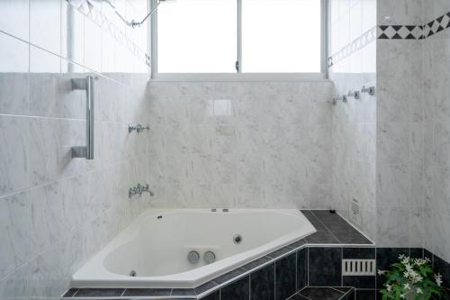 クロヌラにあるThe Oceanfront Sanctuary Spa & Parkingの浴槽と窓のある白いバスルーム