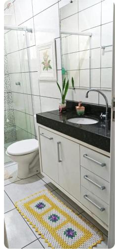a bathroom with a sink and a toilet and a mirror at Casa com ar condicionado quente e frio in Paranavaí