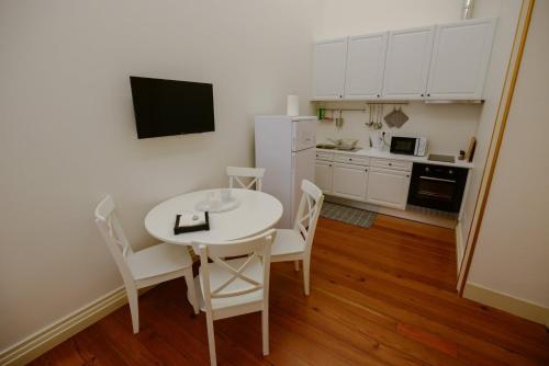 a kitchen with a white table and chairs and a white refrigerator at GuestReady - O Ateneu GuestHouse in Ponta Delgada