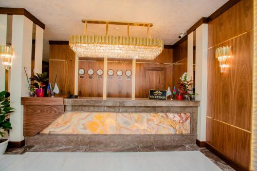 a lobby with a large chandelier and a counter at Adisson Hotel Baku in Azadliq avenue in Baku