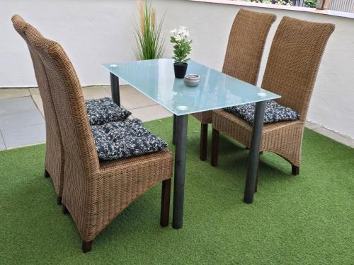 a glass table and two wicker chairs with flowers on it at Mary Haus in Blasbach