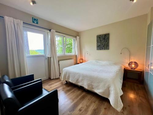 a bedroom with a bed and a chair and a window at Modern holiday home 5 rooms in Durbuy